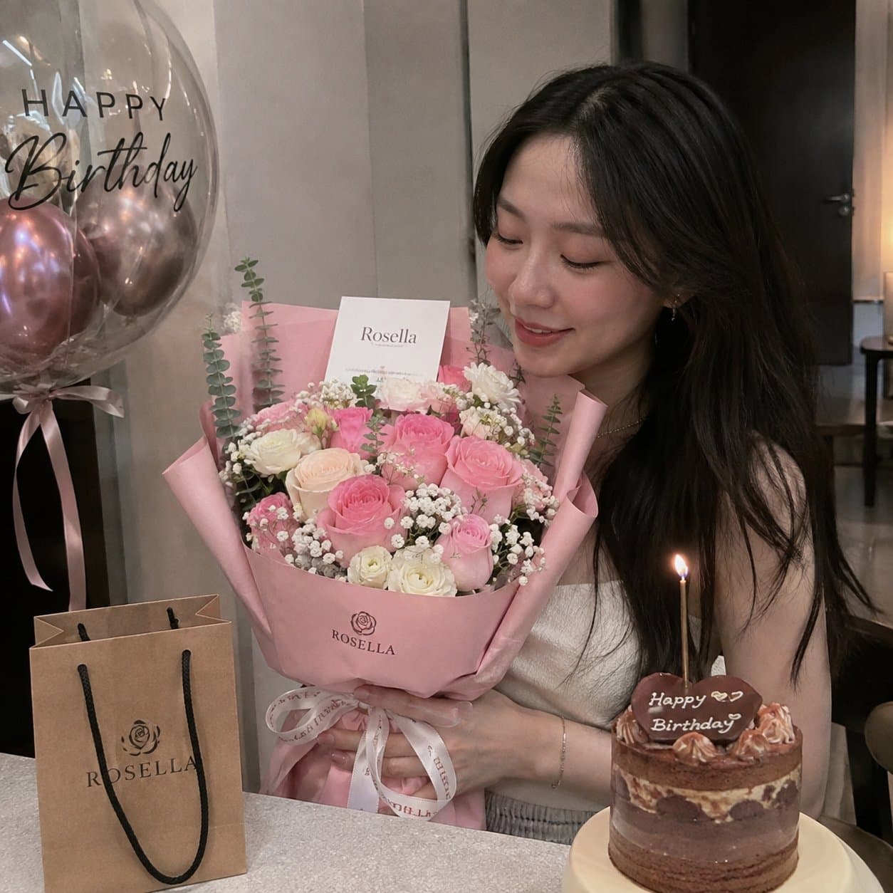 A birthday customer enjoying a pink Rosella bouquet beside a celebration cake