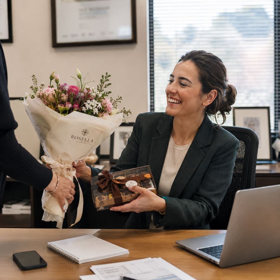 A professional receiving a Rosella bouquet and chocolates at her desk