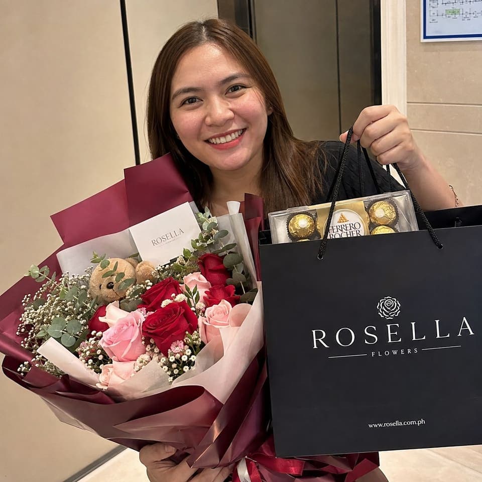A customer holding a red and pink bouquet with chocolates and a Rosella gift bag