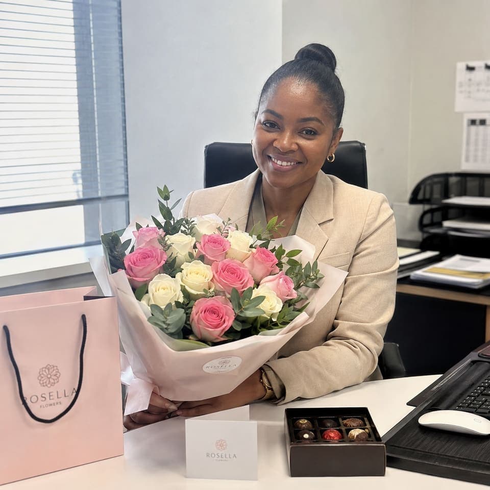 A professional at her desk with a pink bouquet and Rosella gifts