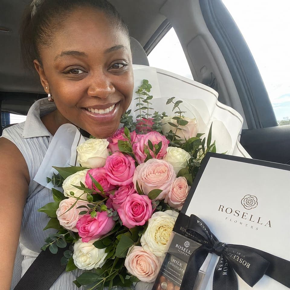 A customer in her car with a pink bouquet and Rosella gift box