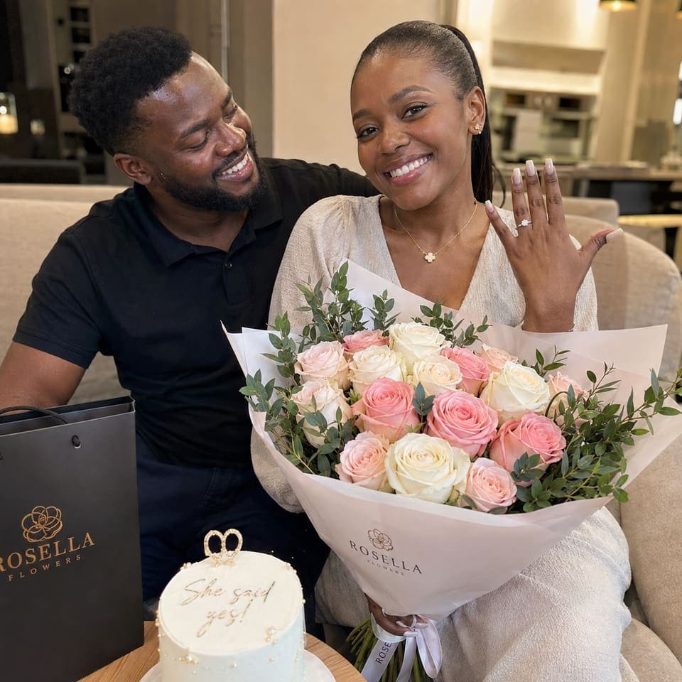 A newly engaged couple celebrating with a bouquet and small cake