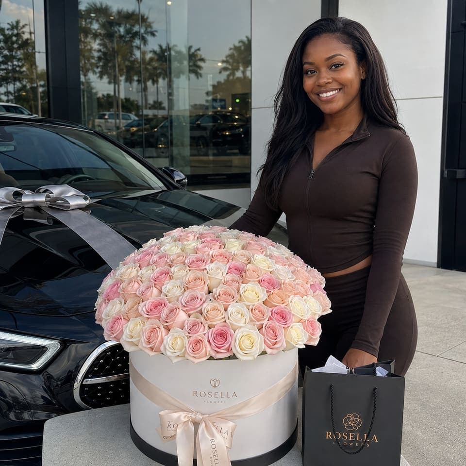 A customer standing beside a car with a large round pink rose arrangement