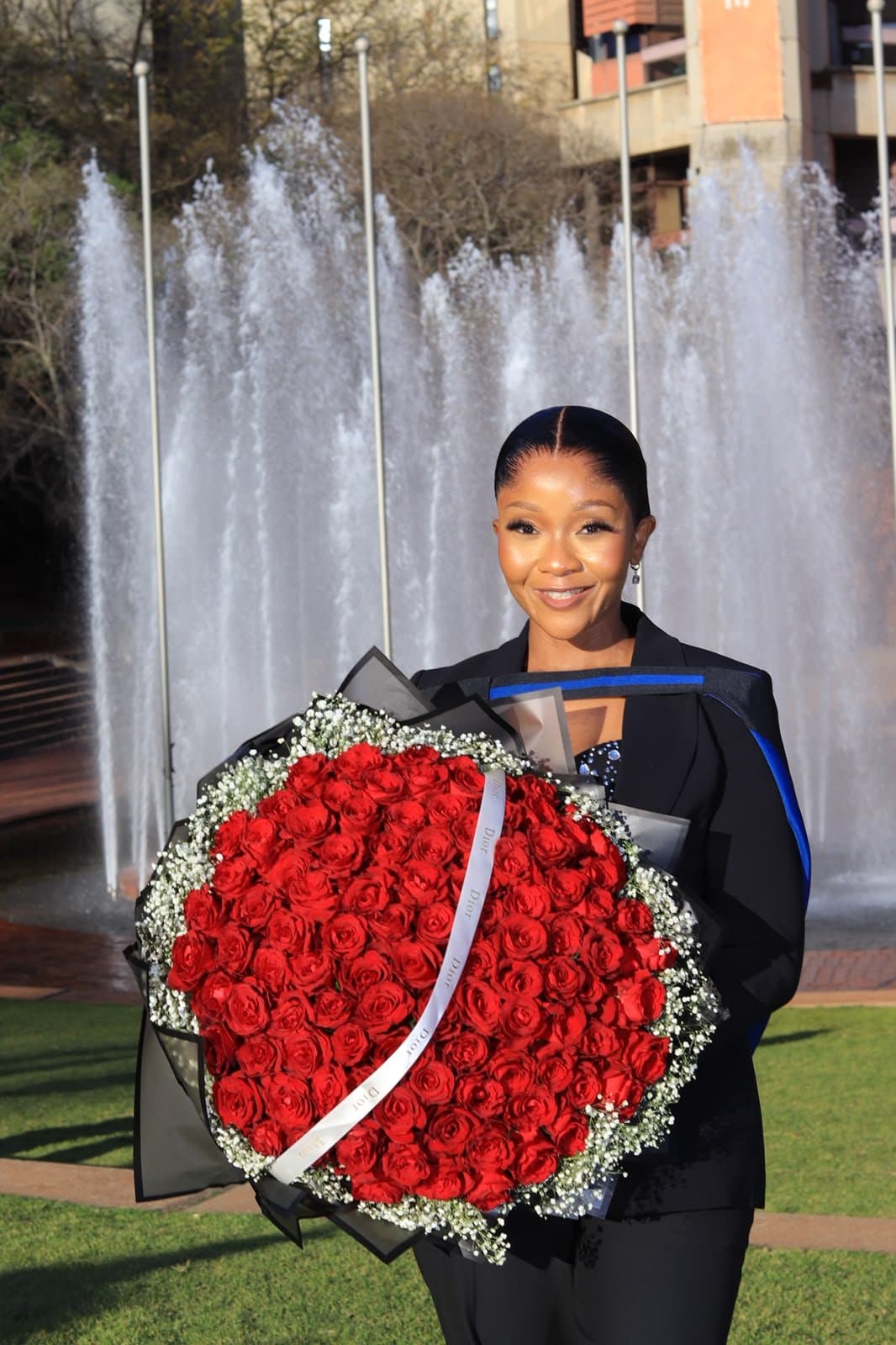 A graduate holding a large red rose arrangement